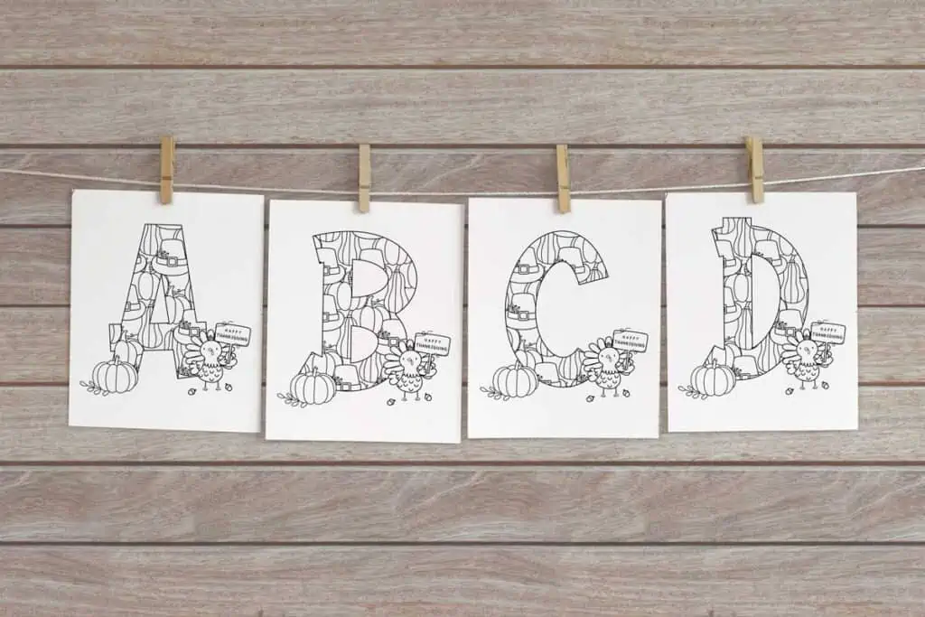 Thanksgiving alphabet coloring pages a, b, c, and d hung on twine with clothespins to make a banner