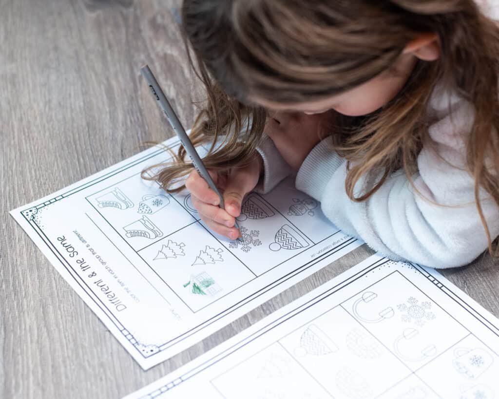 A young child coloring a different and the same worksheet page