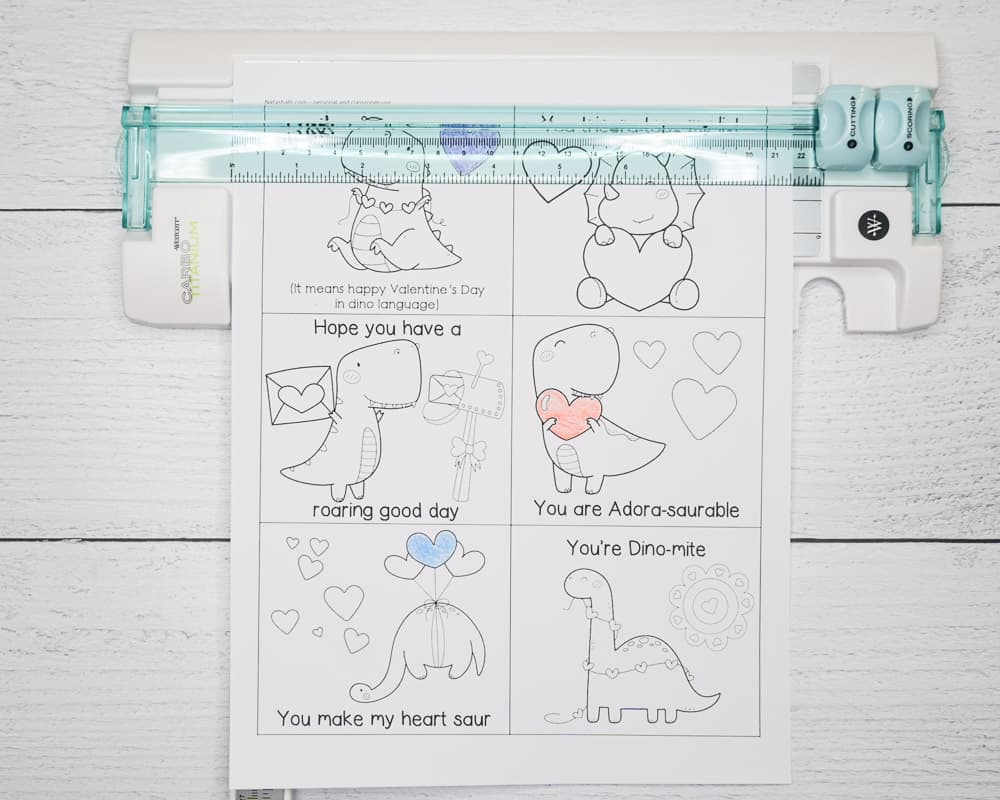 Using a paper trimmer to cut out free printable black and white Valentine's Day cards with dinosaurs
