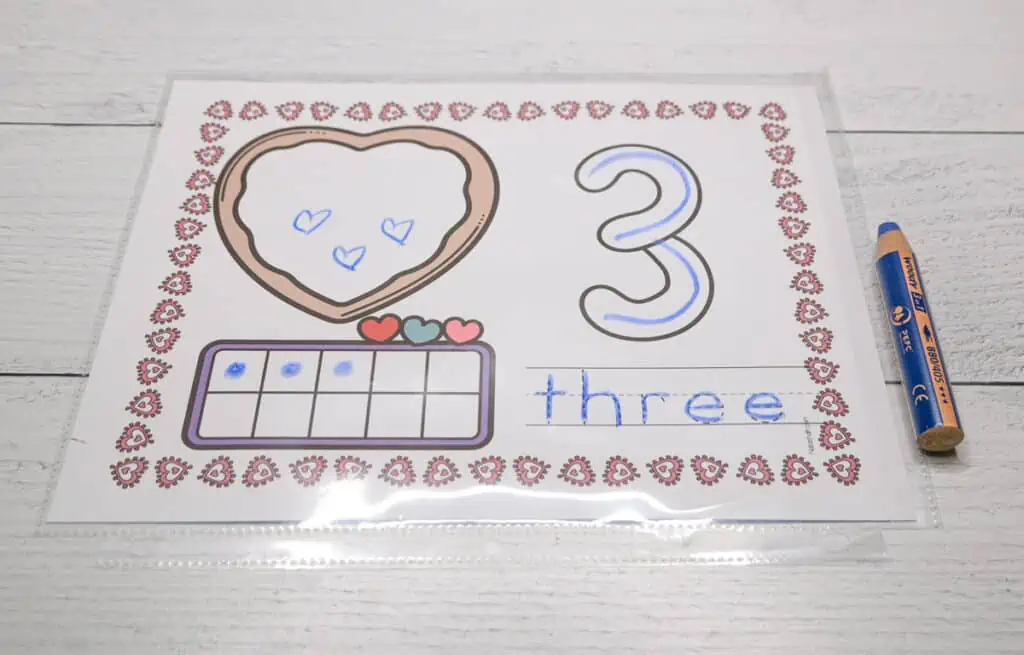 A number three Valentine's Day themed counting mat with a blue Stabilo Woody pencil