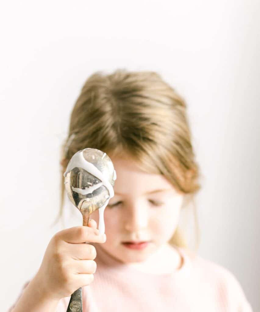 A young girl holding a dripping spoon