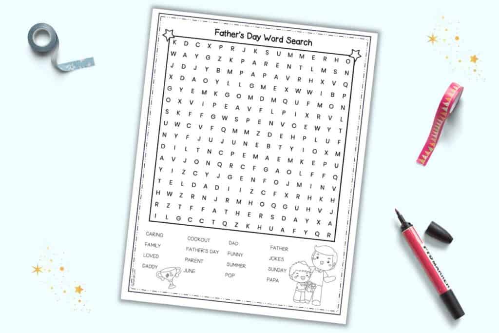A mockup of a free printable Father's Day word search. It is on a light blue background with wash tape and an open marker pen.