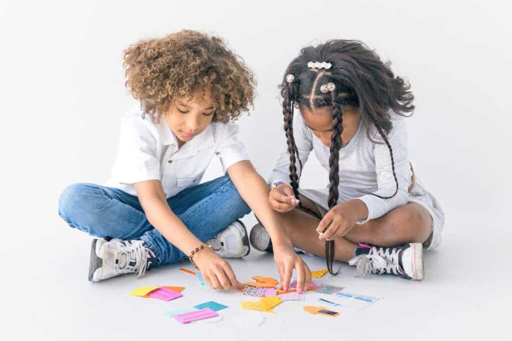 Two children playing with brightly colored crafting materials