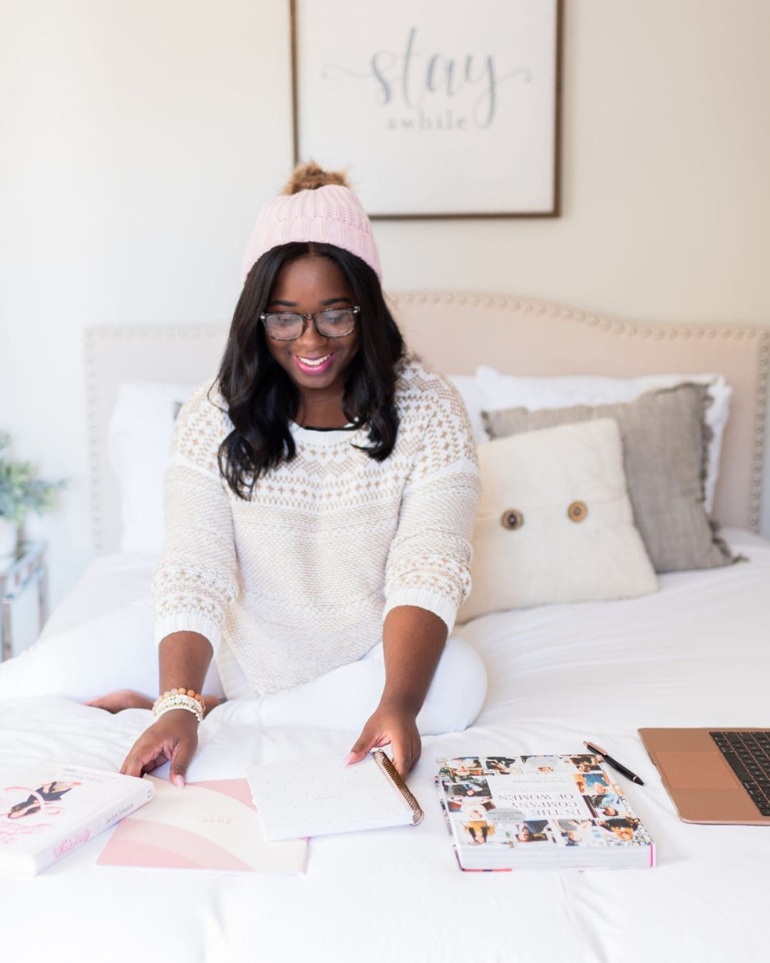 A photo of a black woman wearing a pink cap doing planning on her bed