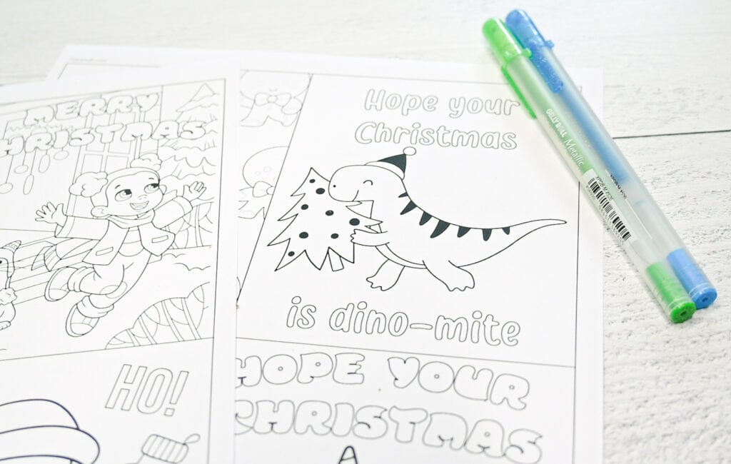 A close up photo of a printable Christmas card with a dinosaur and two gel pens