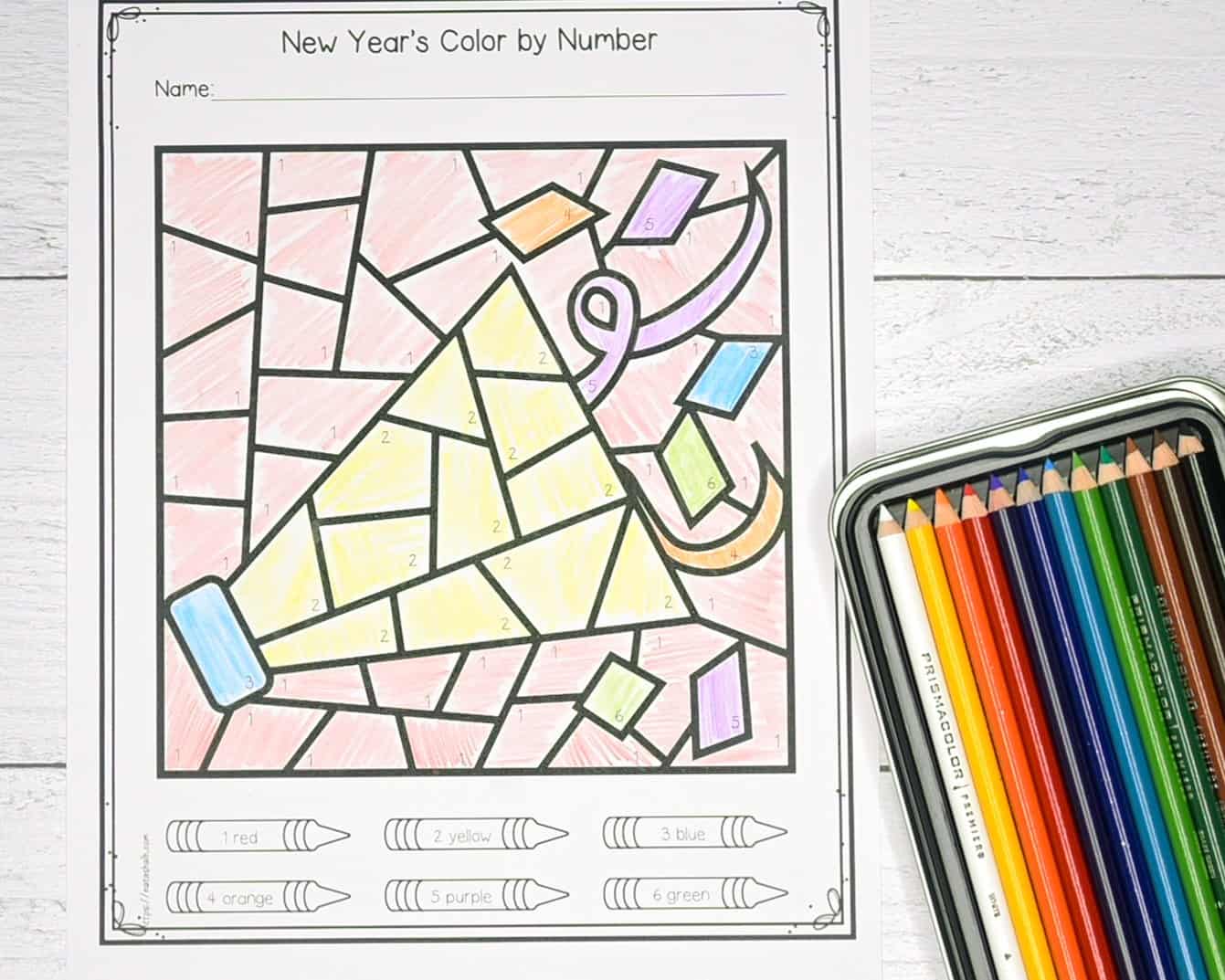 A top down photo of a New Year's color by number page with a box of colored pencils