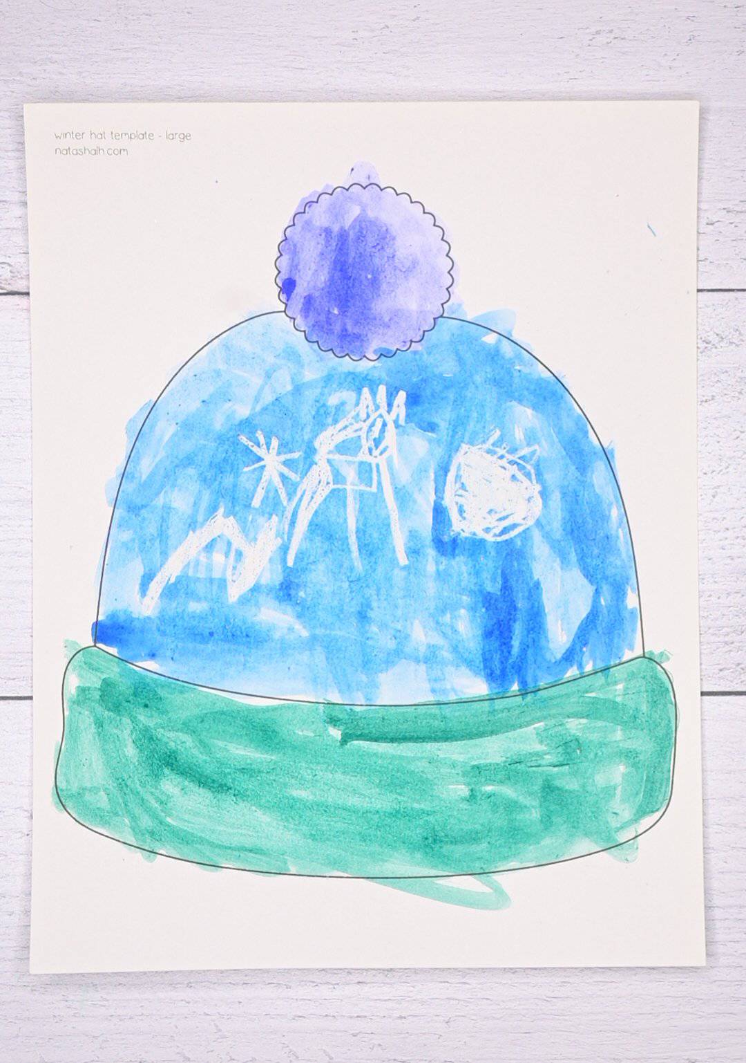 A top down photo of a large winter hat template that has been watercolor painted by a child.