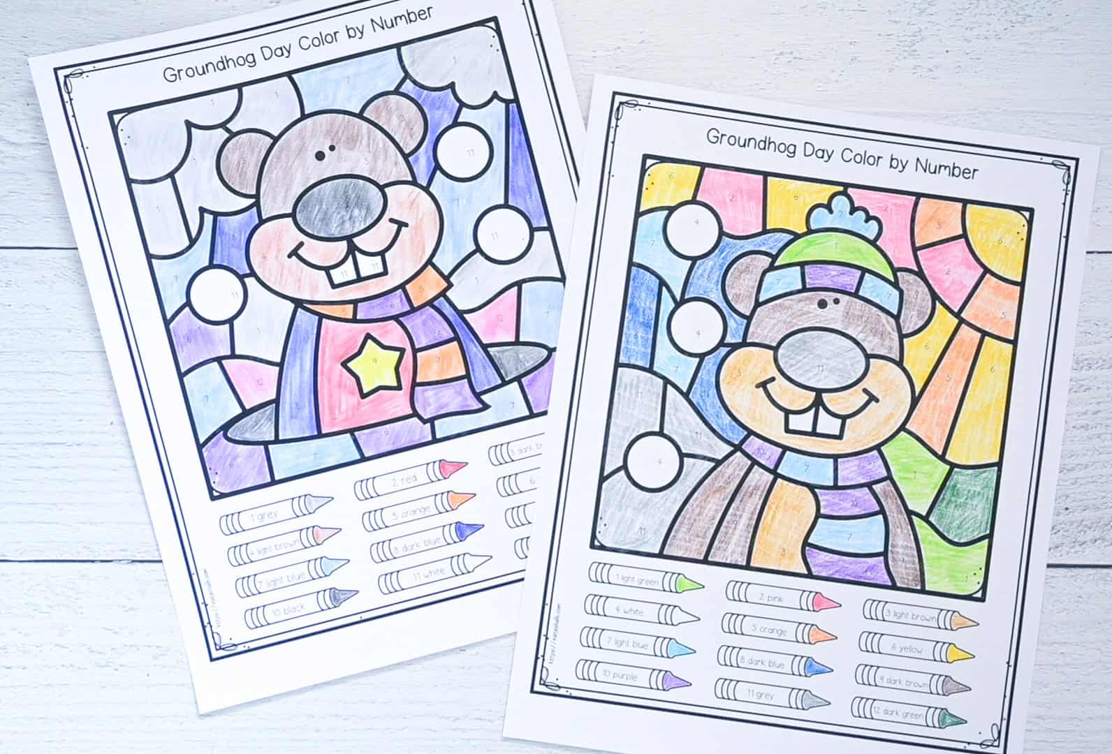 A photo of two completed Groundhog's Day color by number pages for kindergarten students 