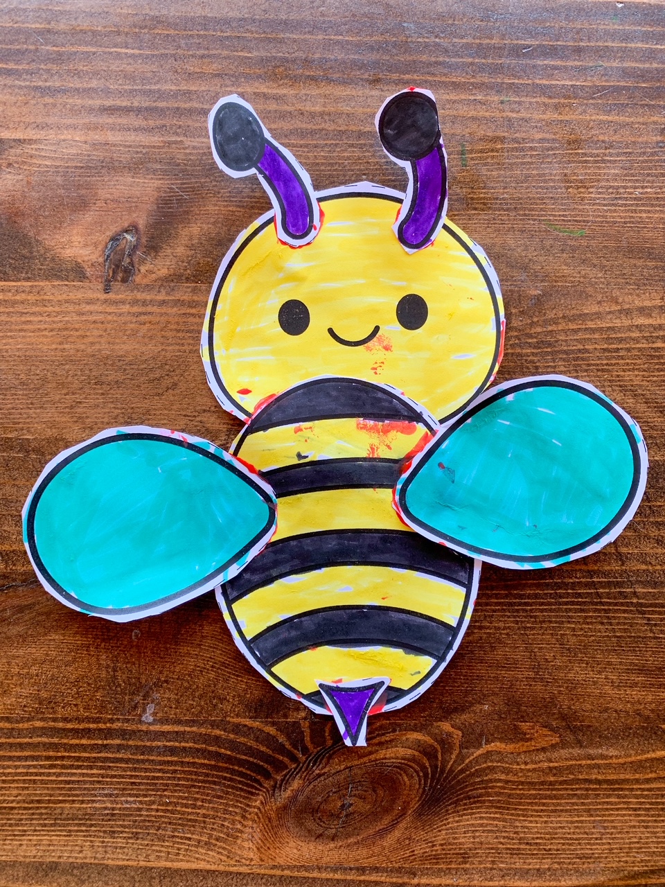 A completed cut and paste bee craft on a wooden table