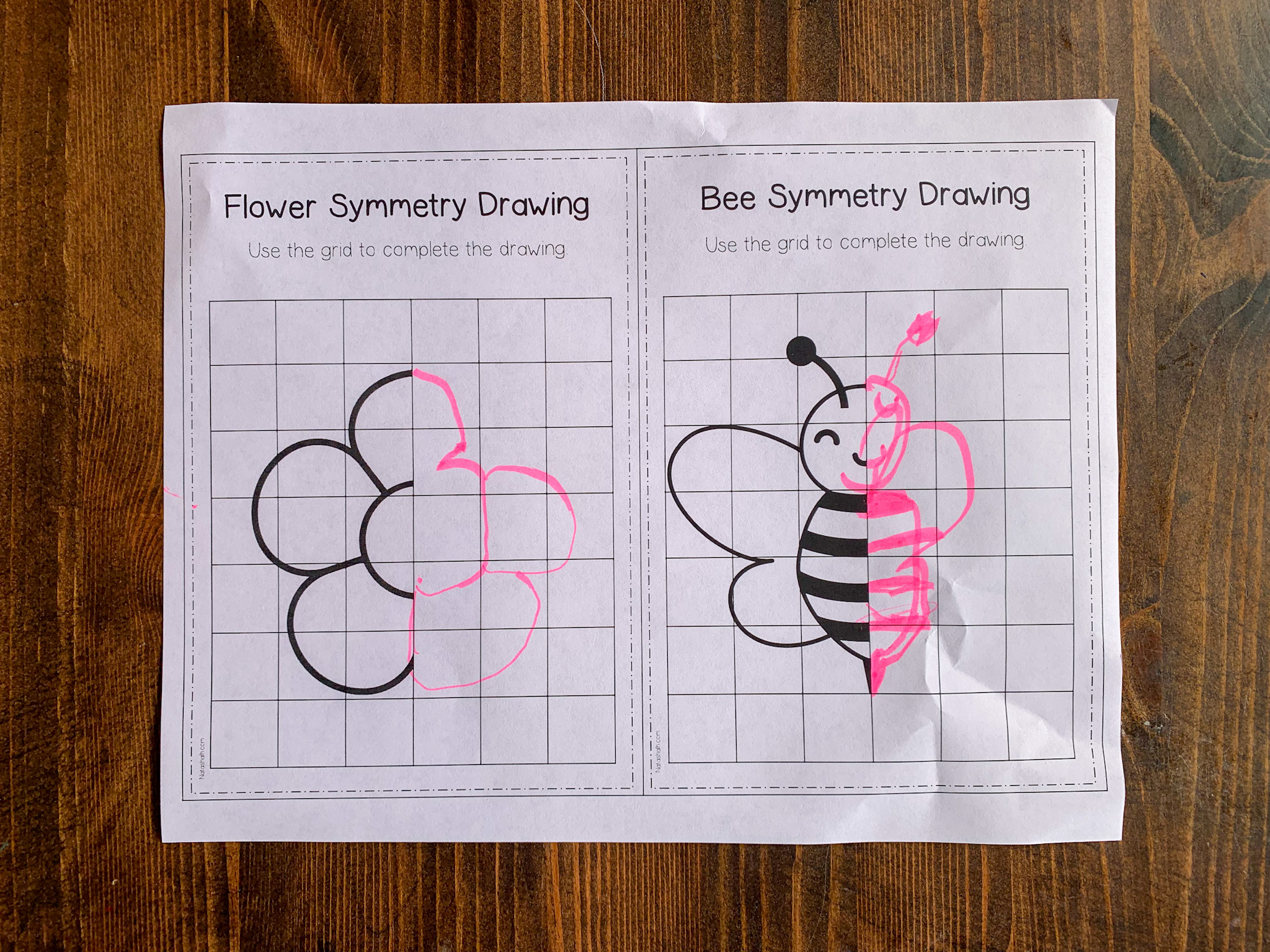 A top down photo of a spring themed symmetry drawing worksheet with a bee and a flower