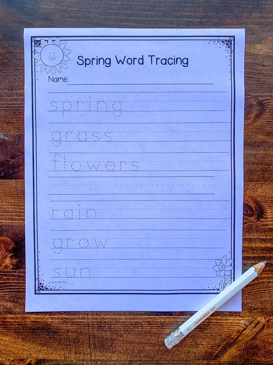 A top down photo of a spring word tracing worksheet with a Channie's preschool pencil