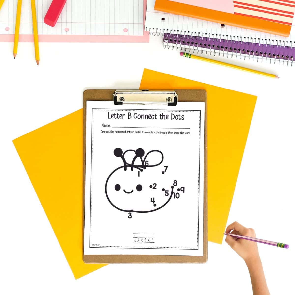 A simple connect the dots page with a bee and numbers 1-10. It is on a desk with papers, pencils, and spiral notebooks.