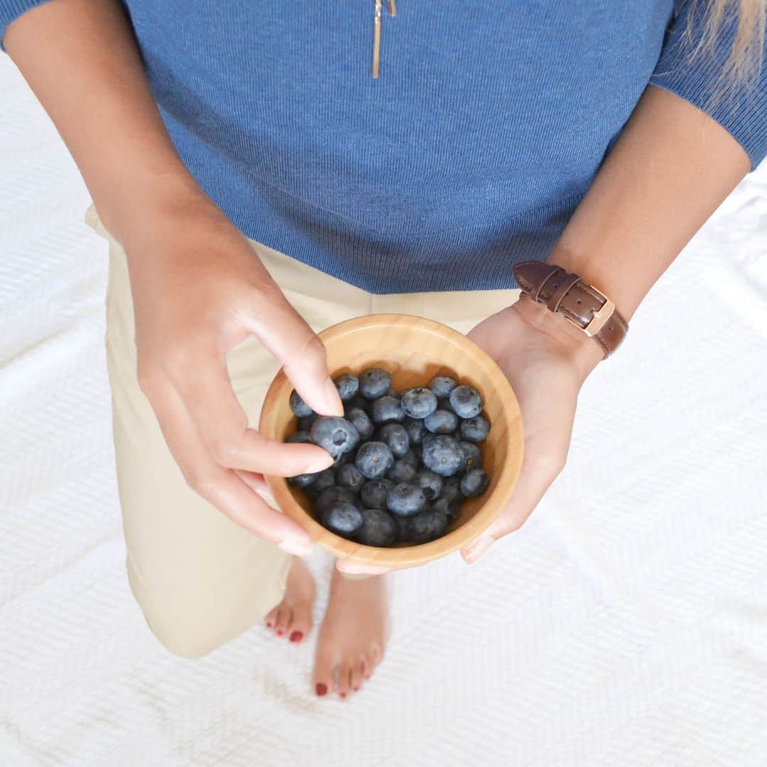 A woman's hands holding a small bowl of blueberries