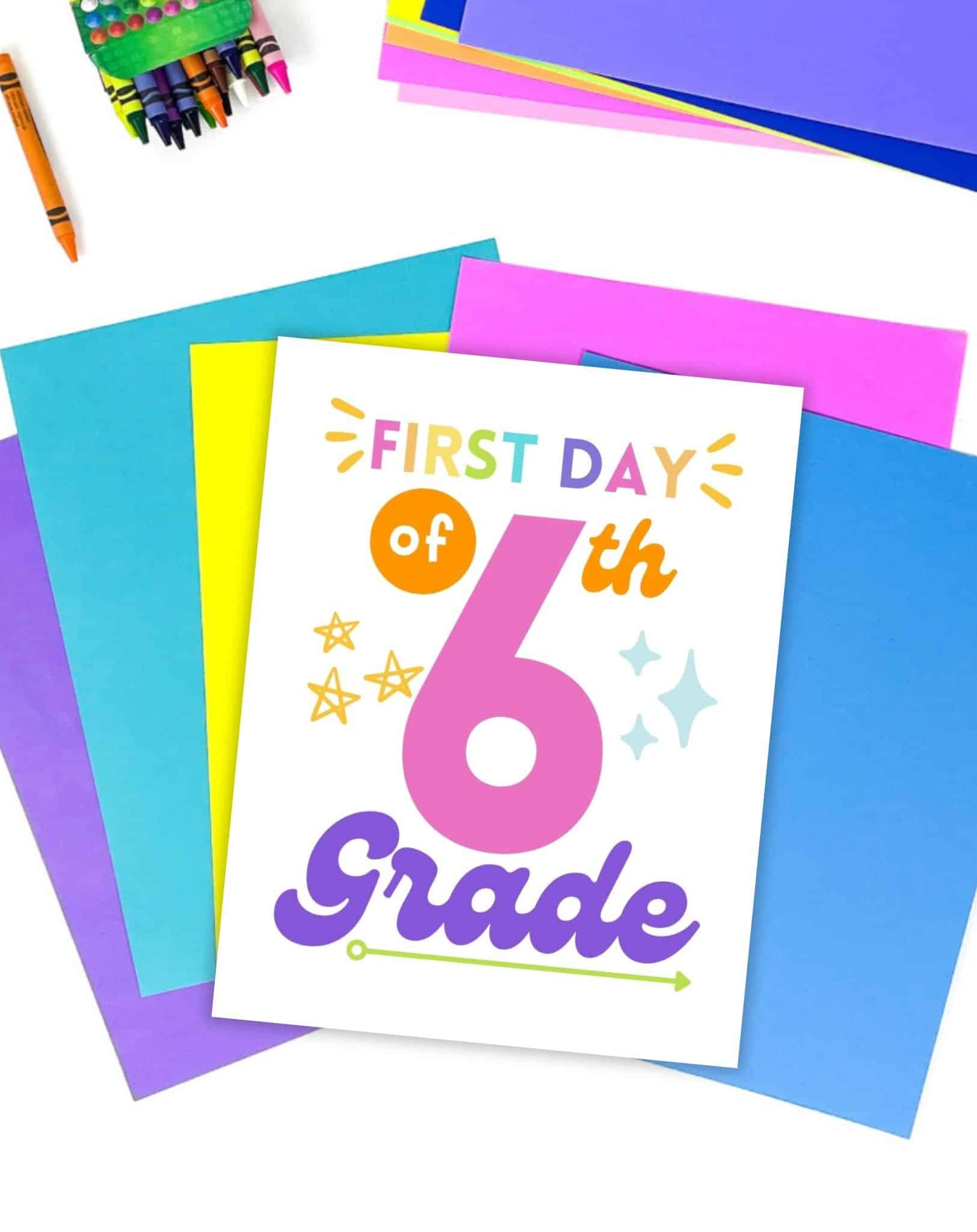 A first day of sixth grade sign on a desk with colorful papers