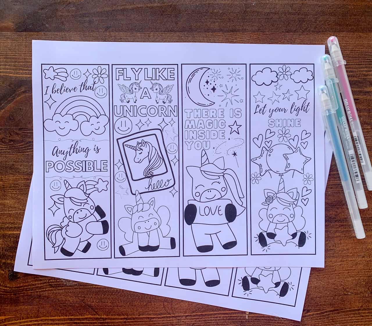 A top down photo of a printed page of unicorn coloring page bookmarks with three gel pens