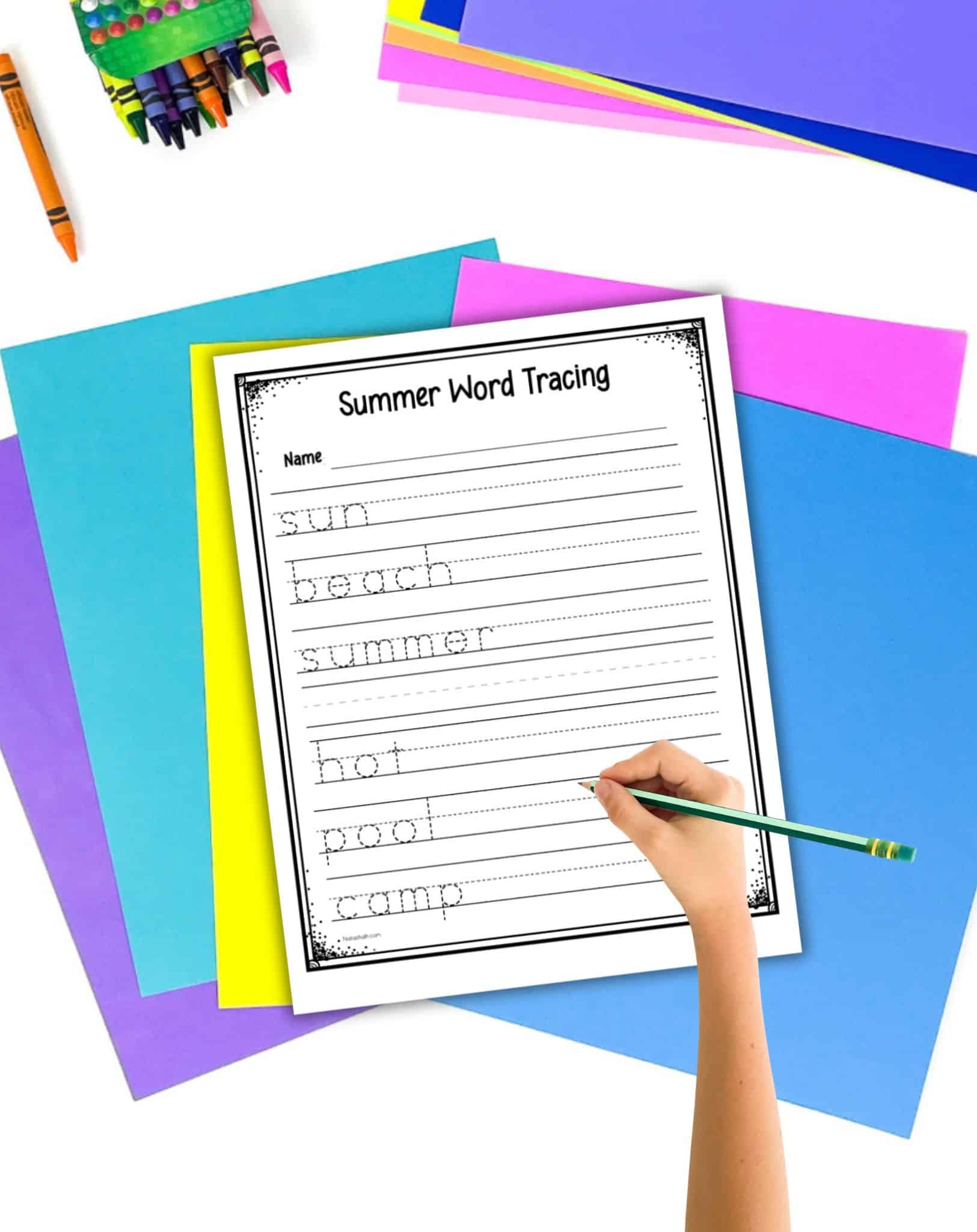 Colorful student desk supplies and a hand with a green pencil hovering over a summer word tracing worksheet 