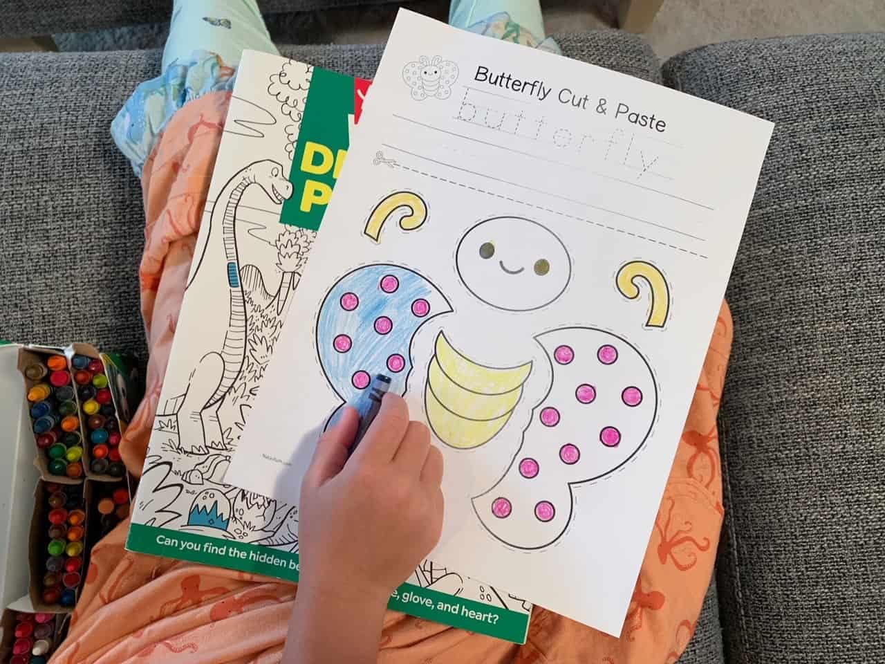 A top down photo of a child coloring a butterfly cut and paste craft printable