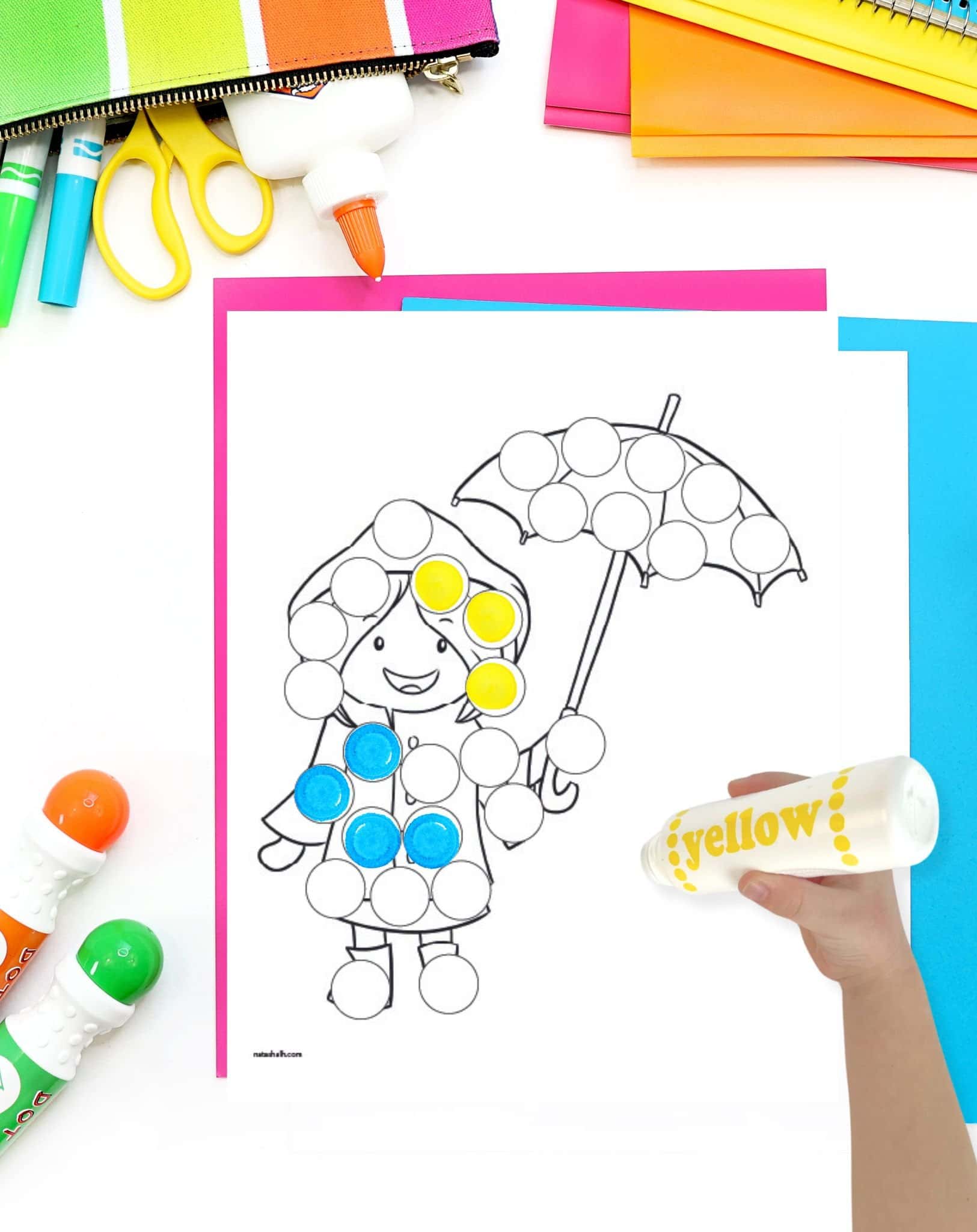 A top down image of a dot marker page showing a girl holding an umbrella. A child's hand is holding yellow dot marker in the foreground