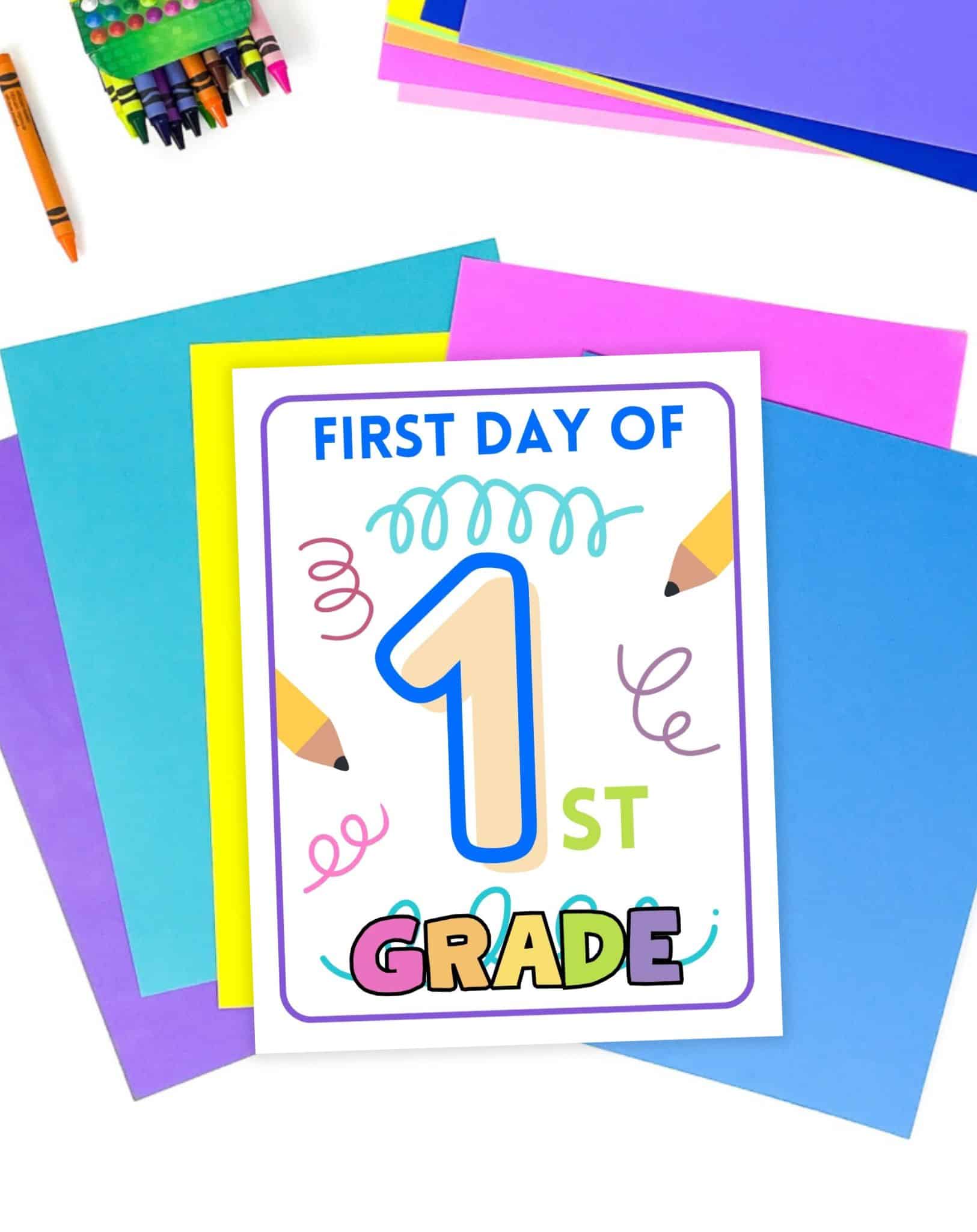 A first day of first grade sign printable on a desk with colorful papers