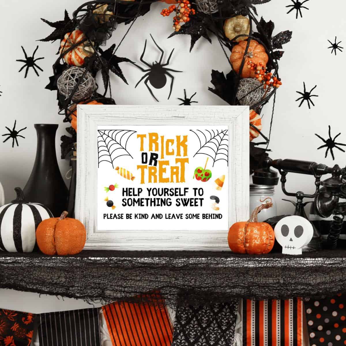 A trick or treat Halloween candy bowl sign in a white frame on a mantle with Halloween decorations