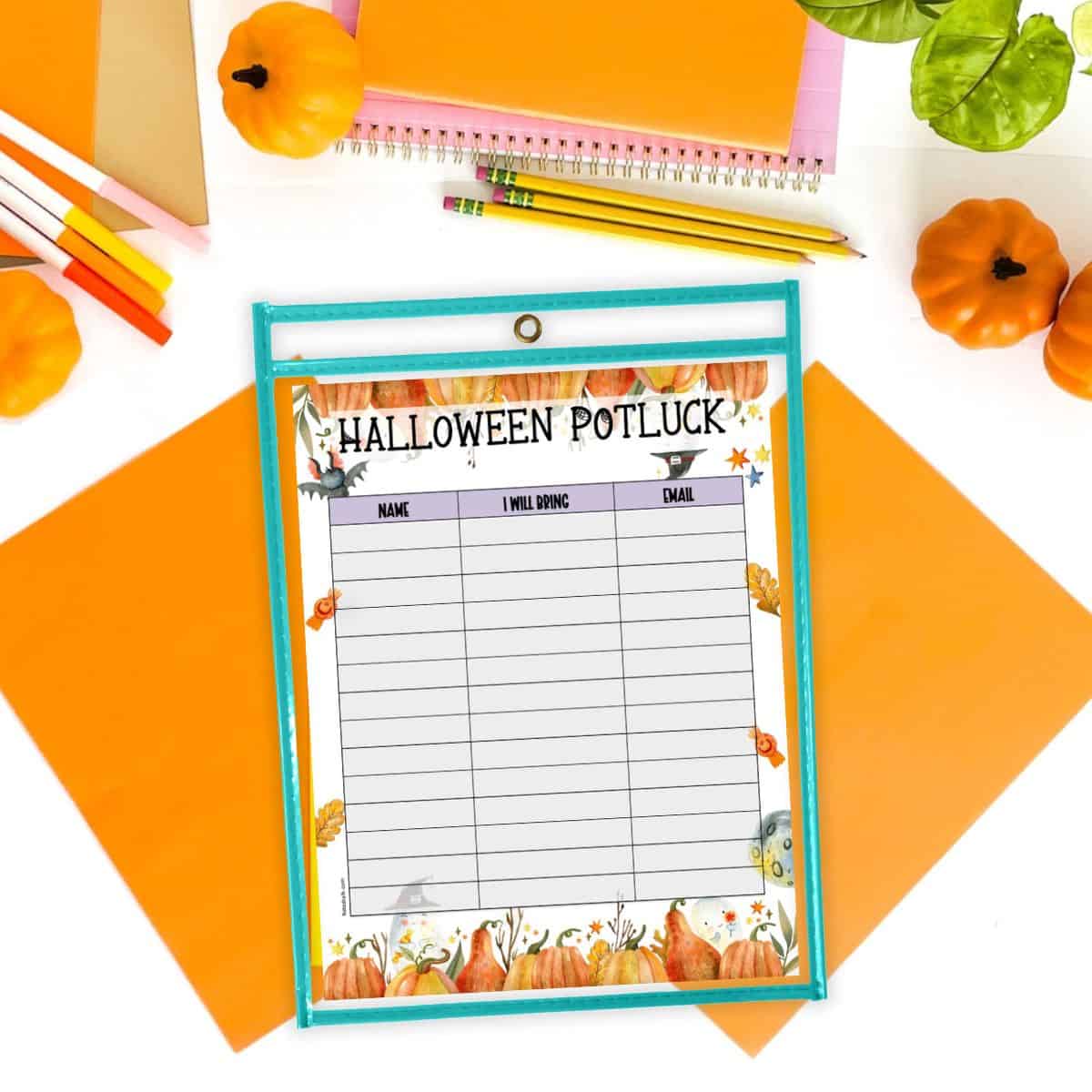 A Halloween potluck sign up sheet printable in a dry erase pocket on a. desk with pencils and pumpkins