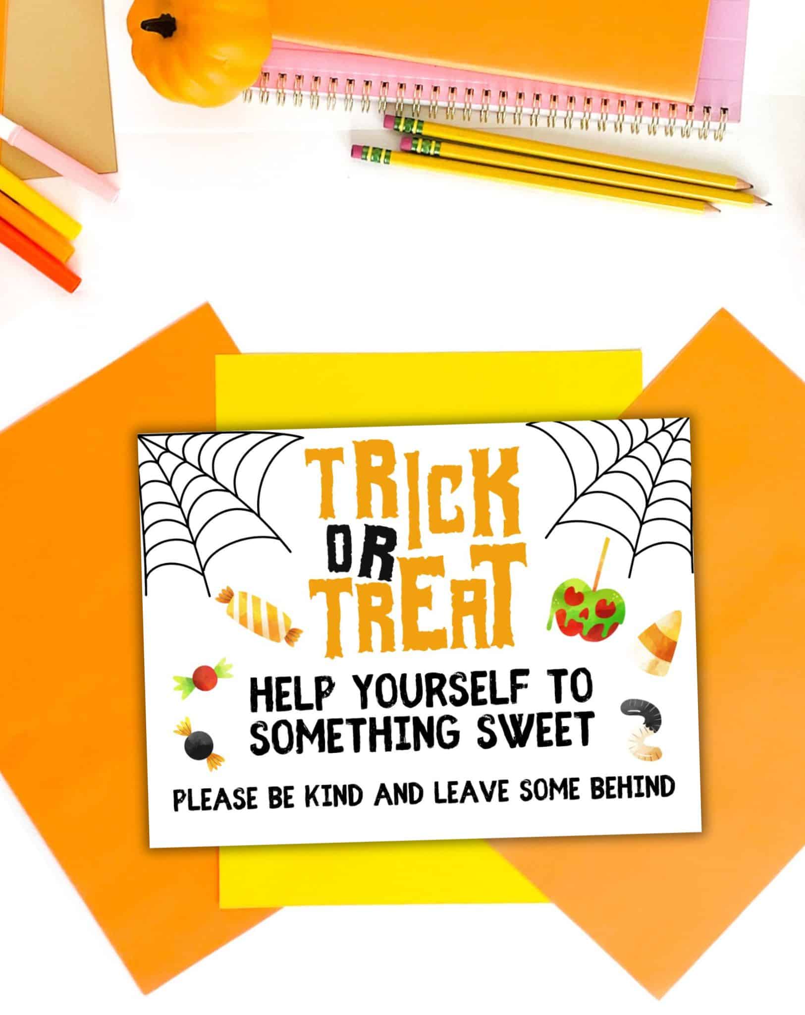 A top down photo of Halloween colored papers and pumpkins with a trick or treat sign printable