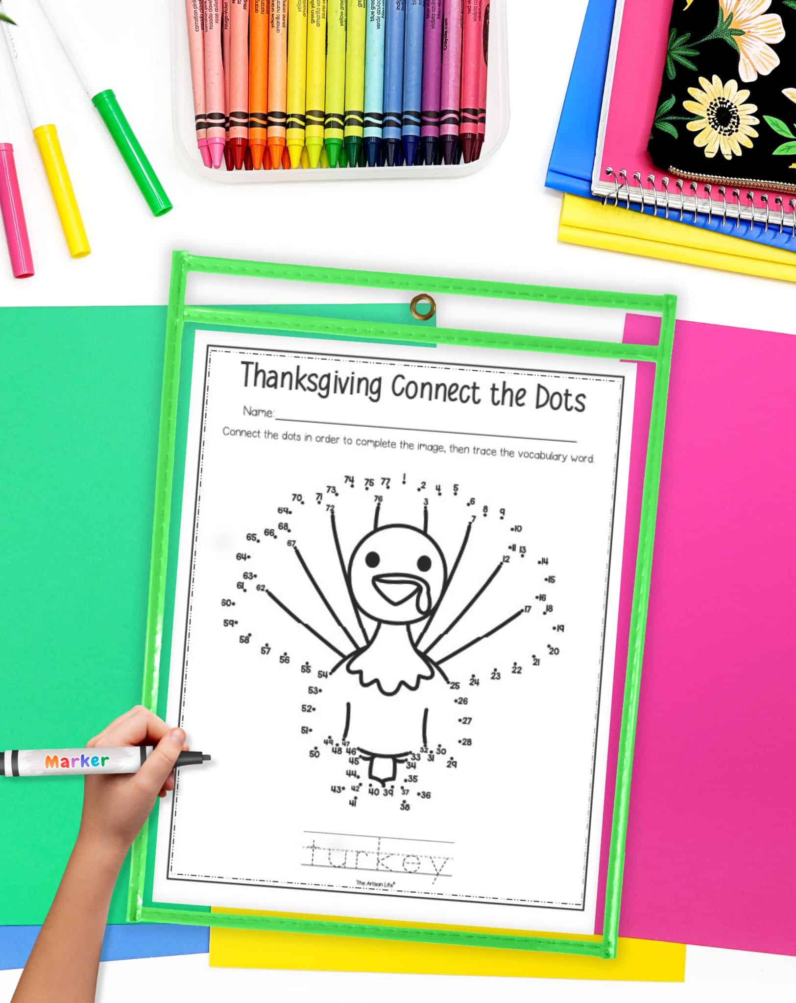 A top down image of a turkey themed connect the dots page in a dry erase pocket. A child's hand holding a marker is visible in the foreground