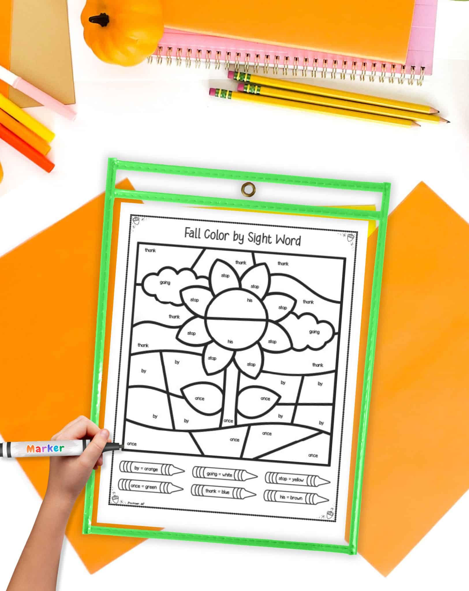 A sunflower color by sight word page in a dry erase pocket on a desk with orange papers