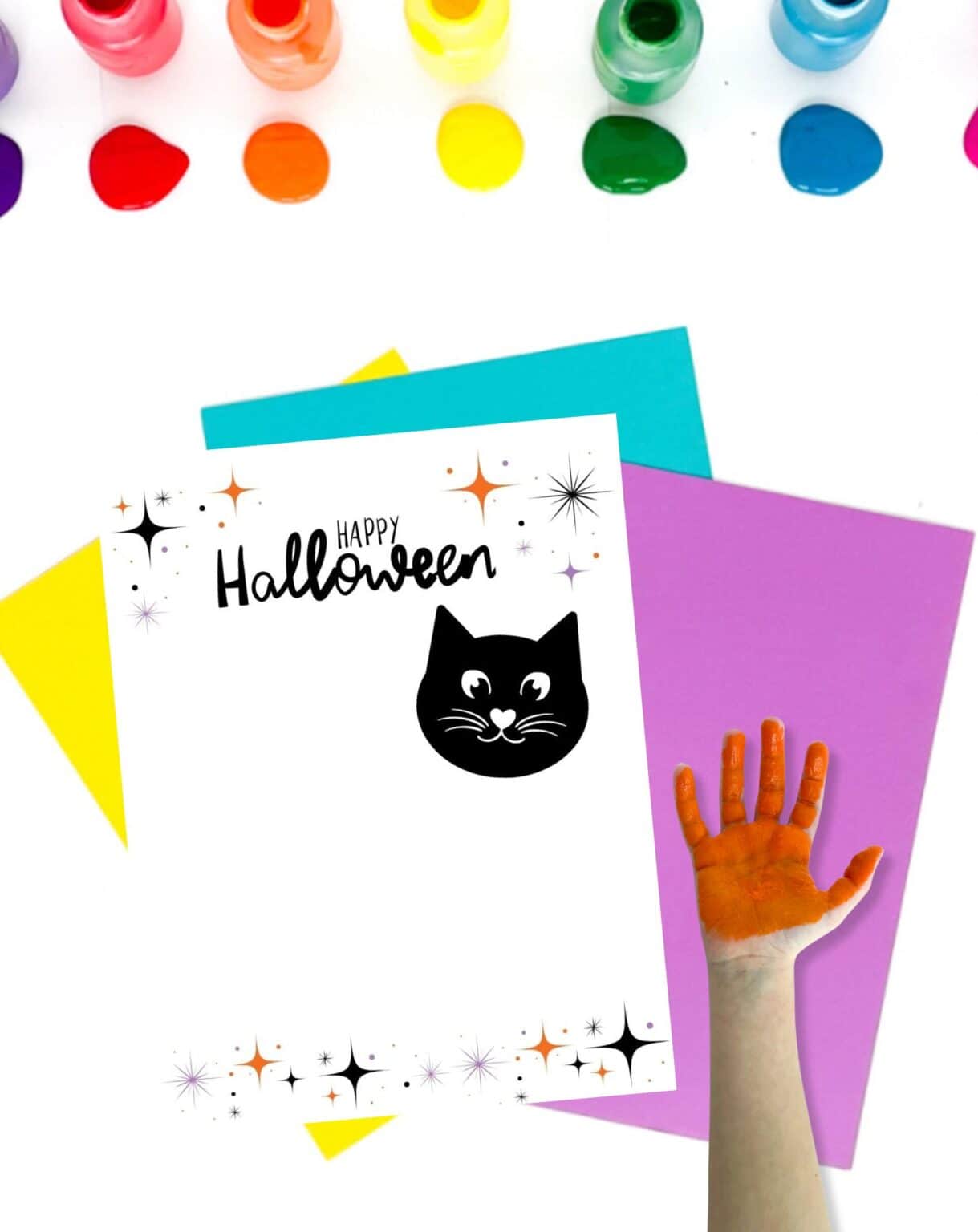 A blank black cat handprint craft on a table with colorful papers and paints