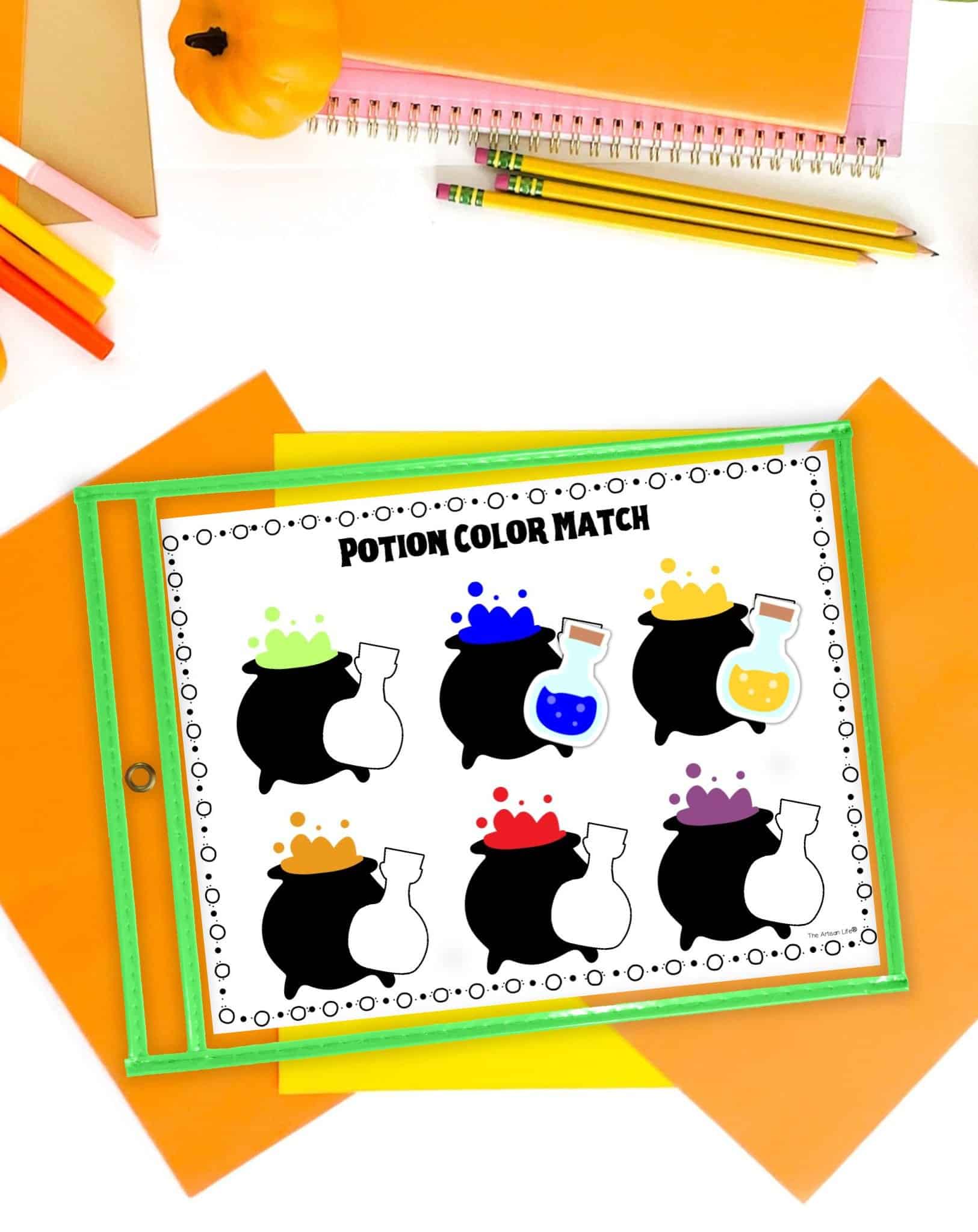 A halloween potion color matching activity in a dry erase pocket on a desk with orange and yellow papers