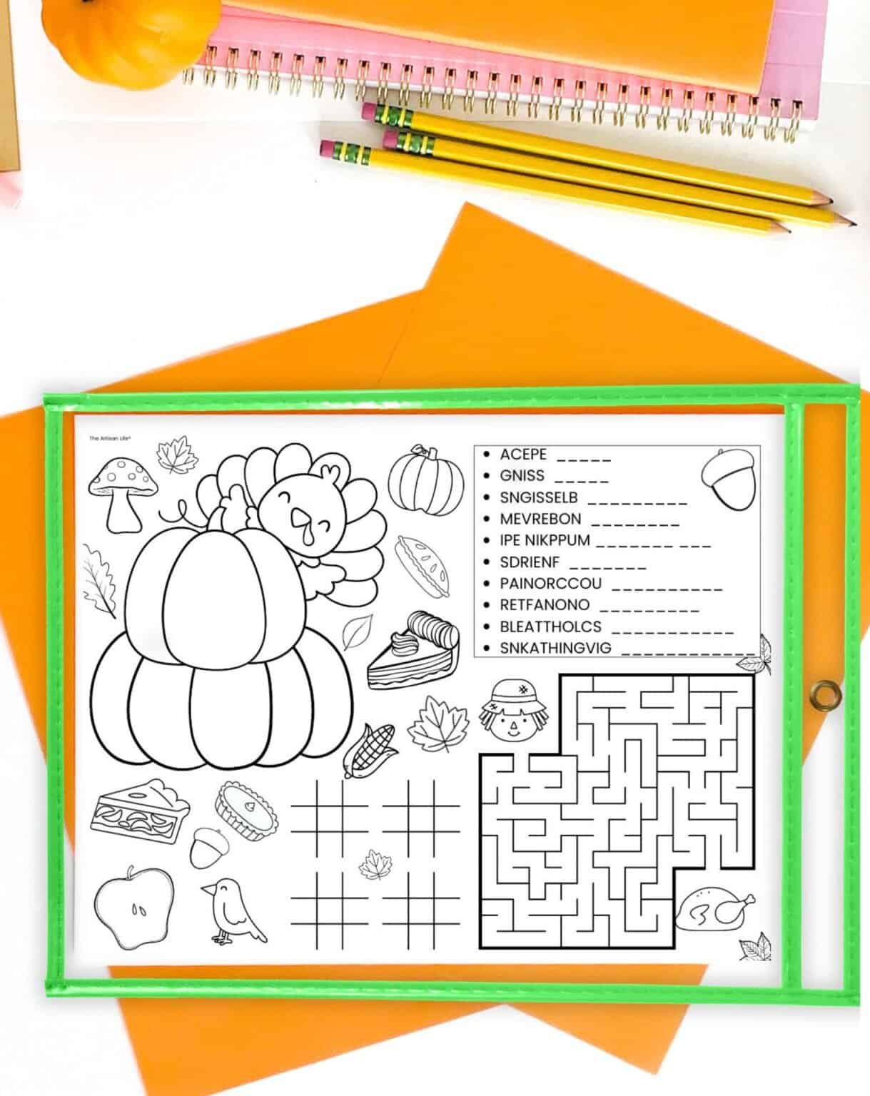 A Thanksgiving activity placemat in a dry erase pocket. It is on a desk with orange papers and pencils.