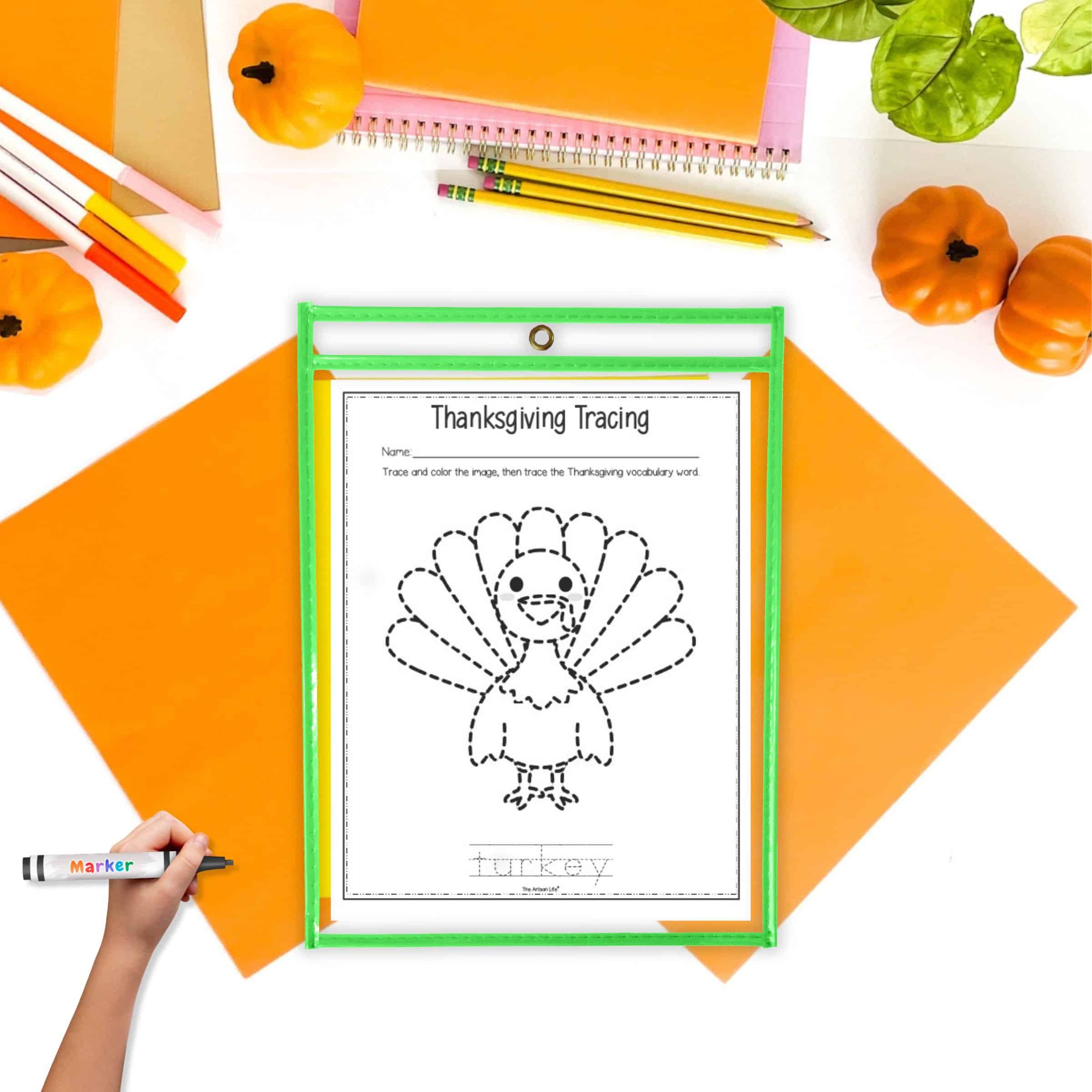 A turkey trace and color page in a dry erase pocket on a. table with orange and yellow papers