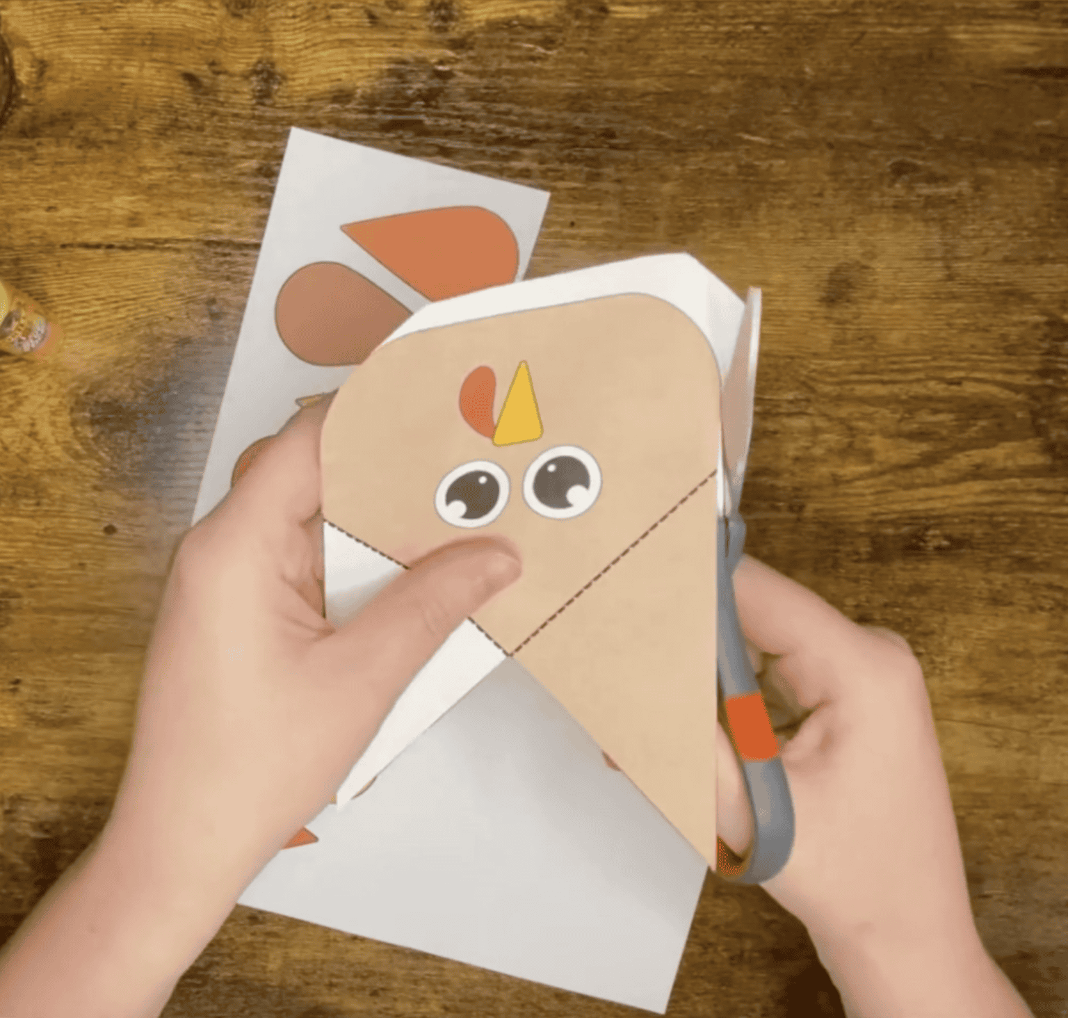 Hands with scissors cutting out a turkey for a turkey corner bookmark craft