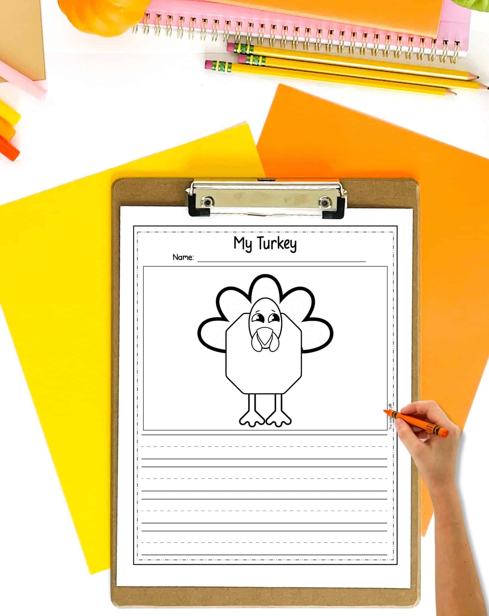 A mockup of a completed roll and draw a turkey printable on a clip board. The clip board is on a table with orange and yellow papers.