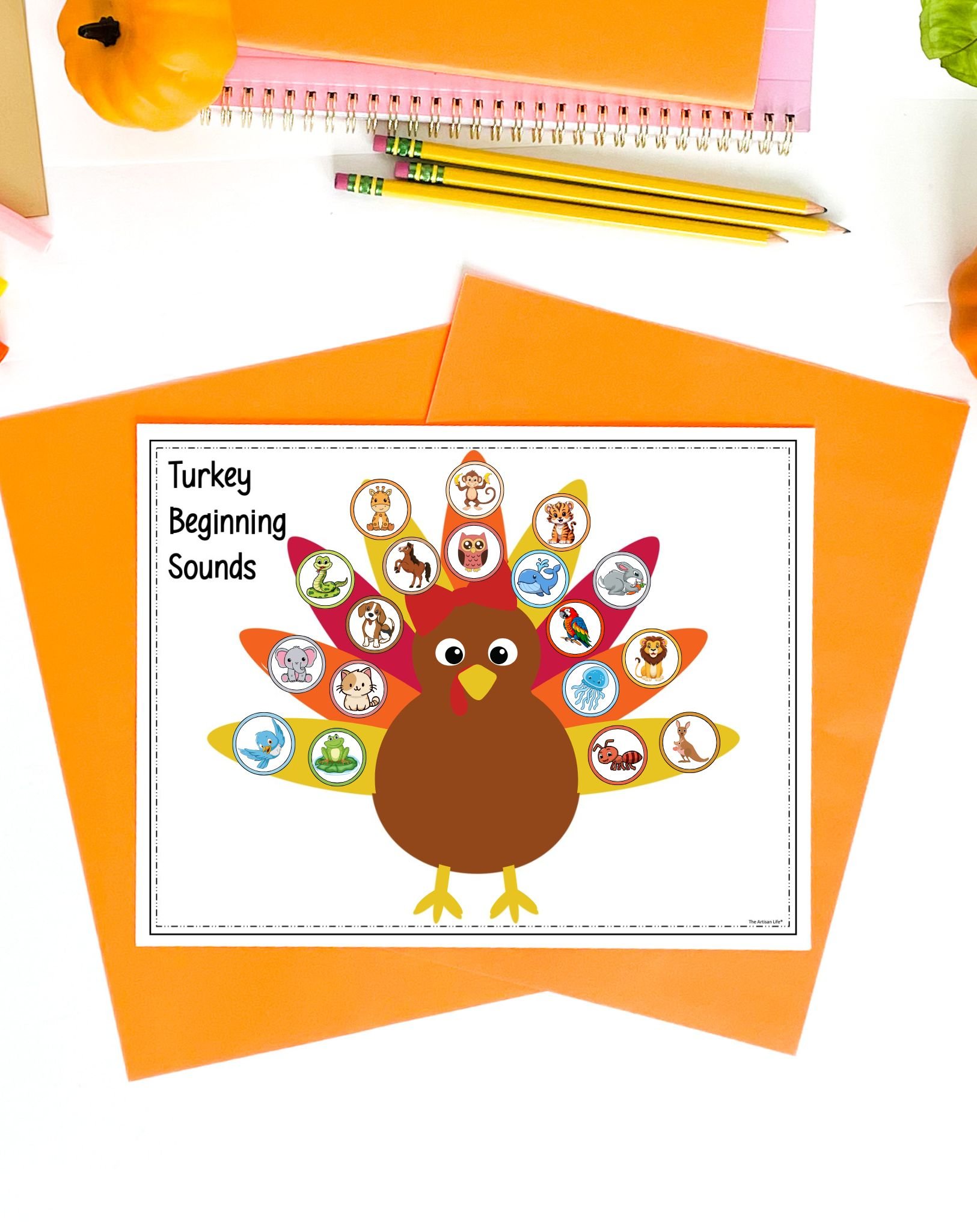 A completed turkey beginning sounds activity on a tale with orange papers and pencils 