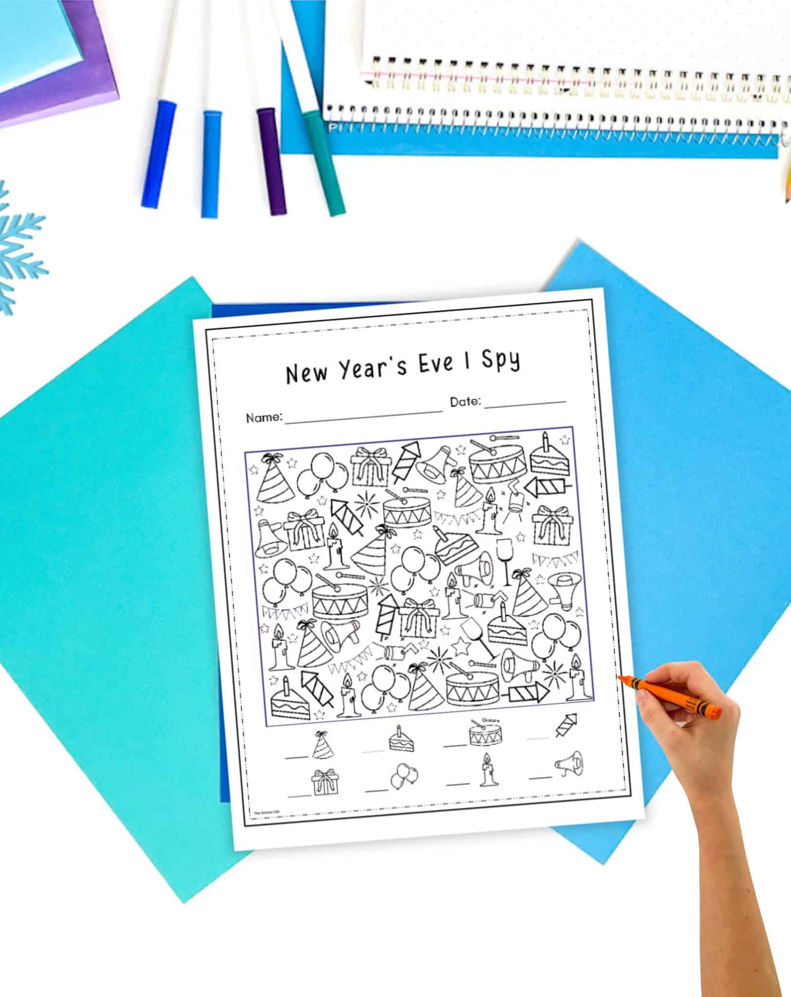 a New Year's Eve I spy worksheet on a table with winter colored stationary items