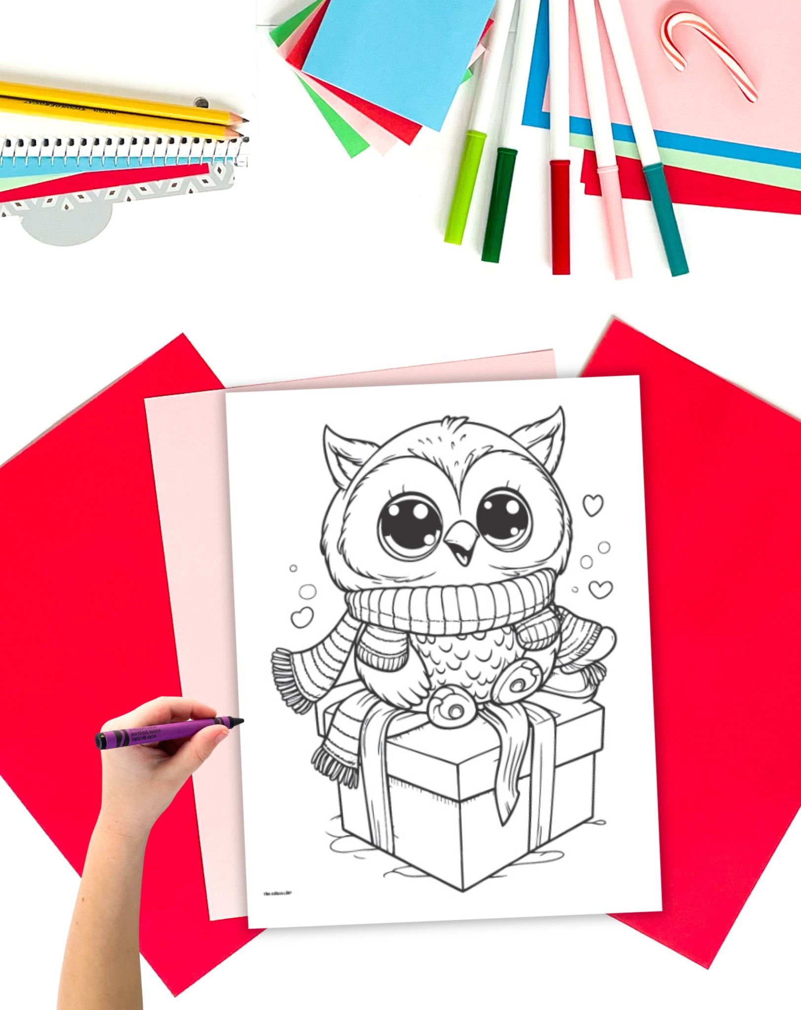 A cute Christmas owl coloring page on a desk with Christmas stationary items