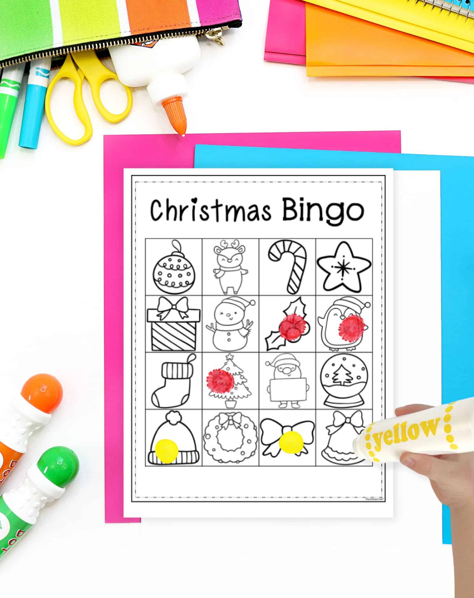 a child's hand using a dauber marker to mark an image on a Christmas picture bingo card