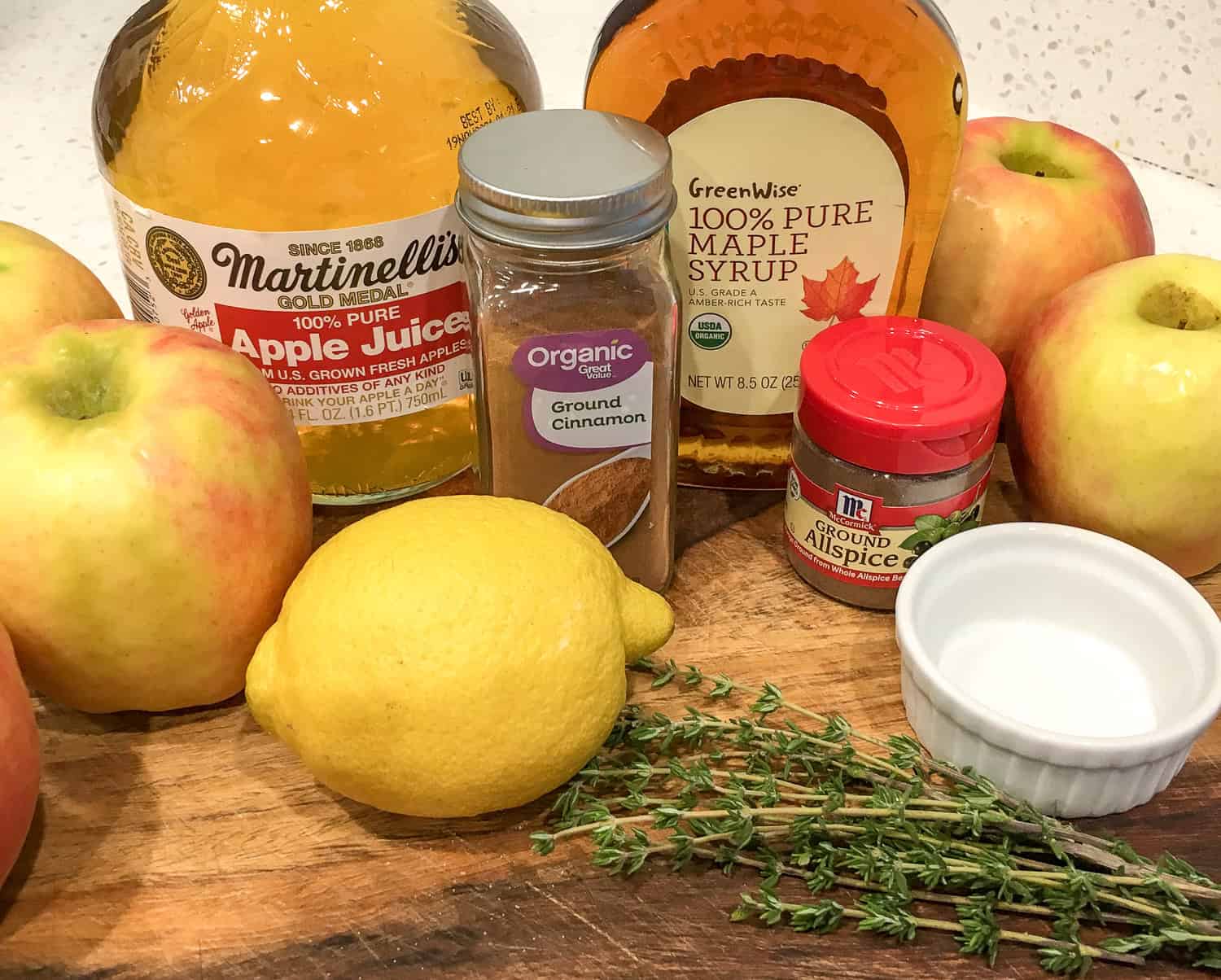 a photo of apple crisp ingredients including maple syrup, cinnamon, apples, and a lemon 