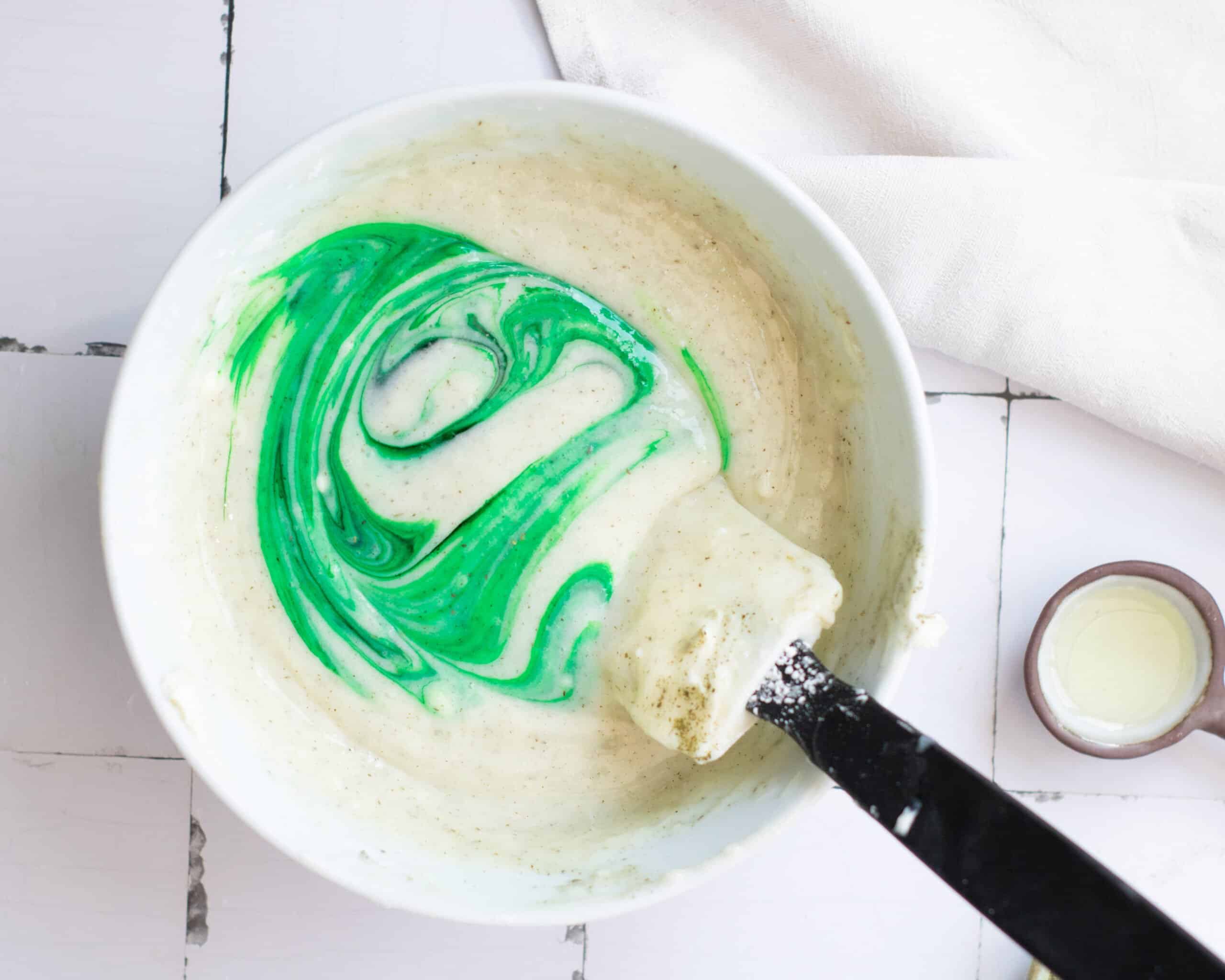 mixing green food coloring into cream cheese