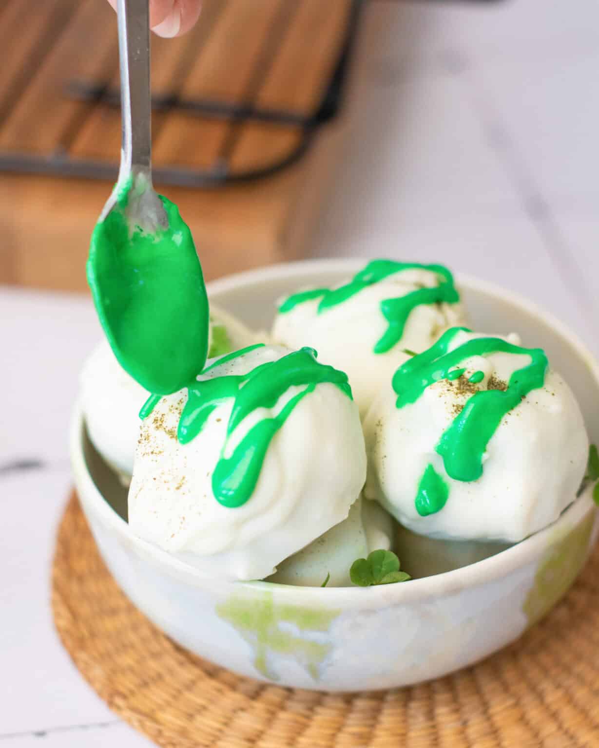 Gluten Free No Bake St. Patrick's Day Truffles drizzling green chocolate on white no bake, gluten free truffle balls