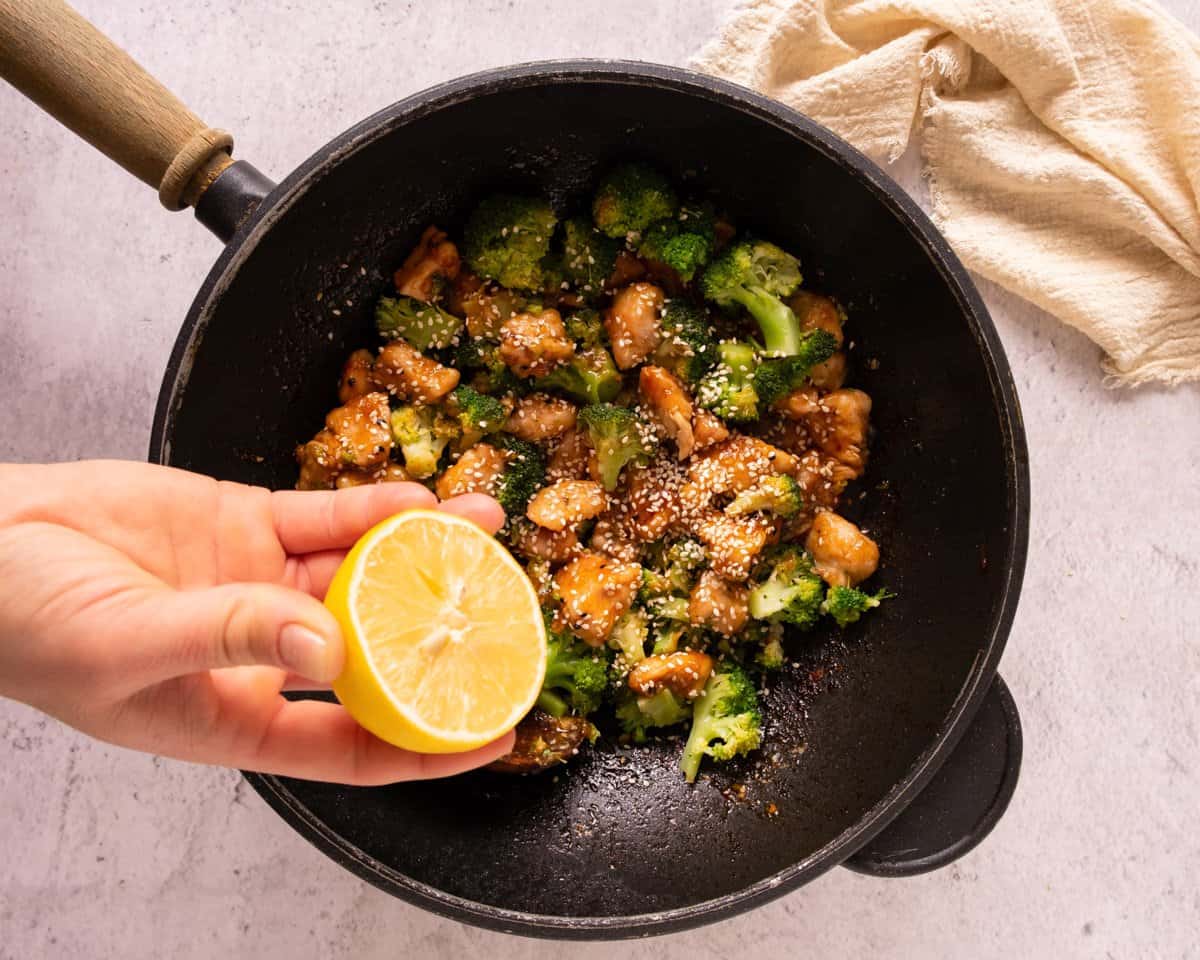 squeezing lemon into a skillet with honey garlic chicken