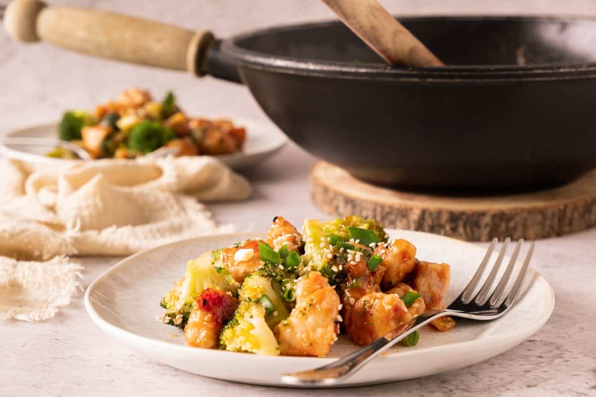 a plate with broccoli and garlic honey chicken. A skillet is visible in the b background 