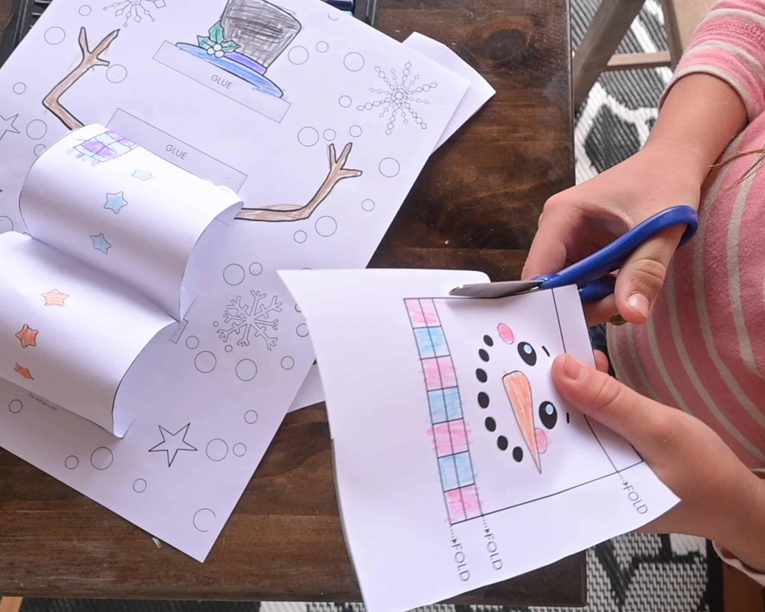 a child cutting out pieces for a 3d snowman craft