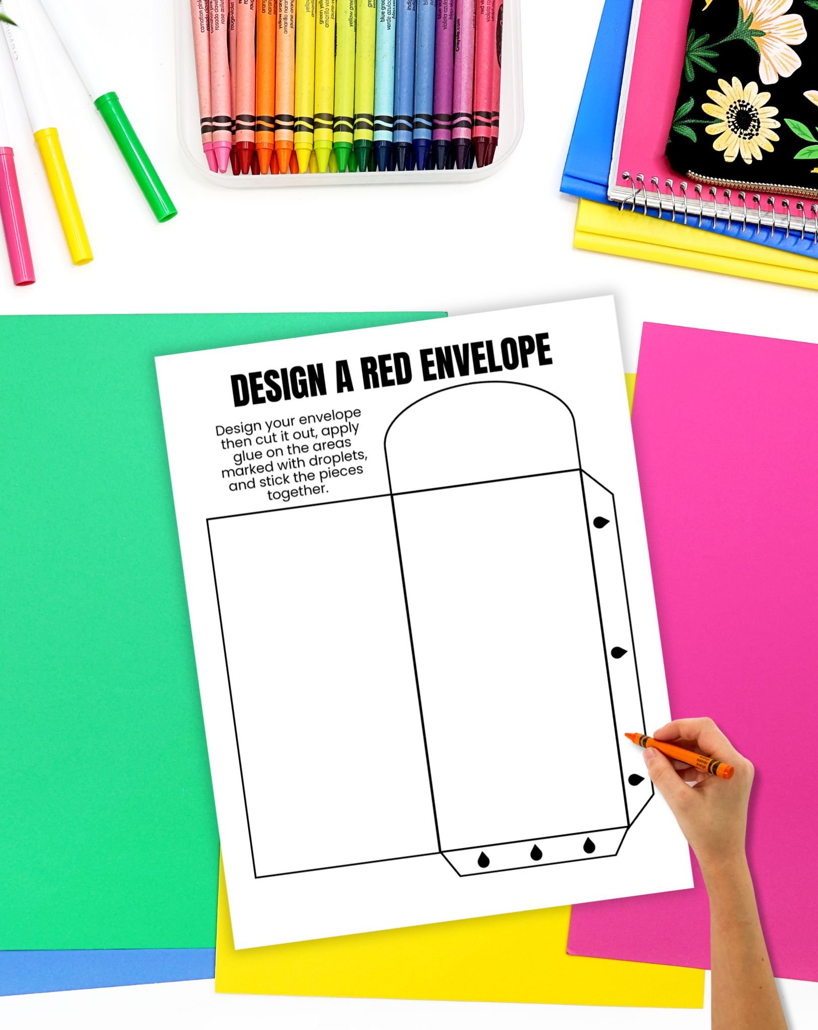 a blank design a red envelope craft on a table with colorful papers and crayons