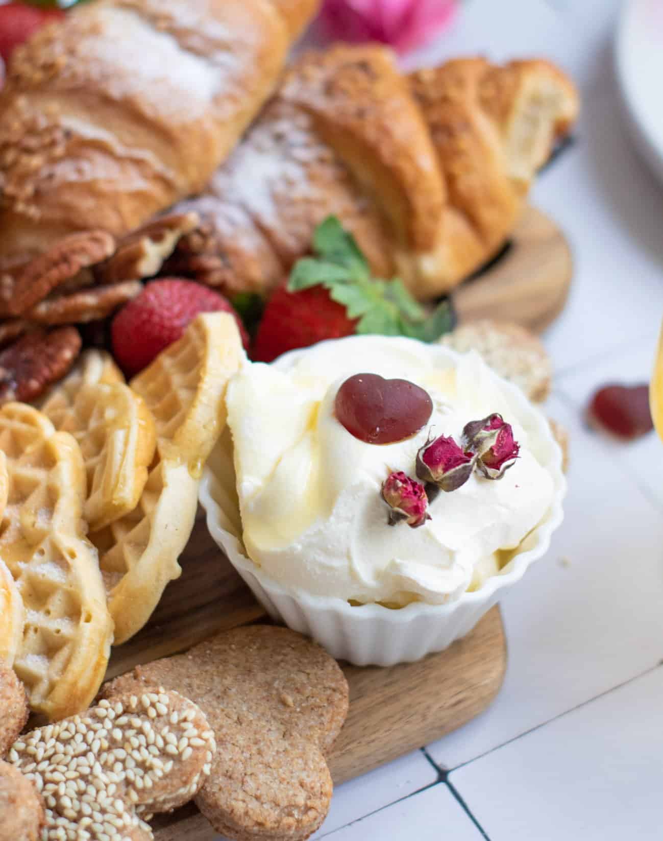 a bowl of cream cheese on a board with pastries