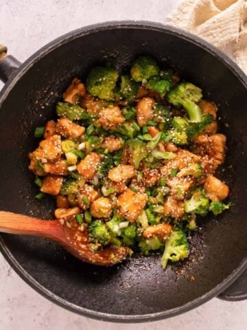 A skillet of garlic chicken bites with broccoli and sesame seeds, showcasing a simple homecooked meal ideal for a healthy weeknight dinner.