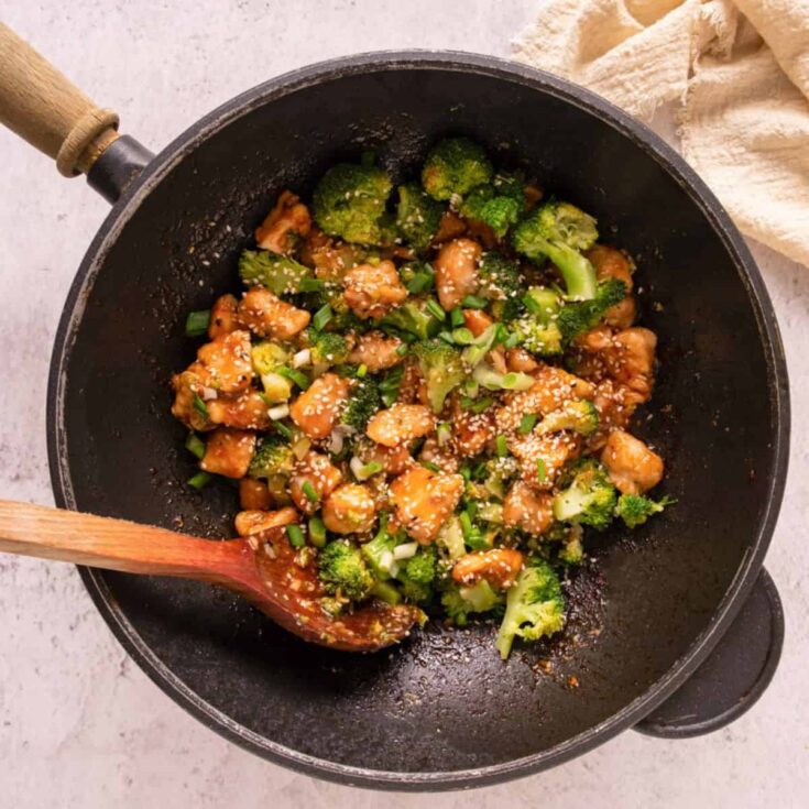 A skillet of garlic chicken bites with broccoli and sesame seeds, showcasing a simple homecooked meal ideal for a healthy weeknight dinner.