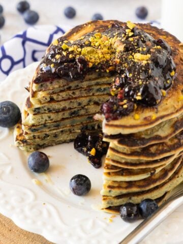 a stack of gluten free blueberry pancakes with homemade blueberry jam on top