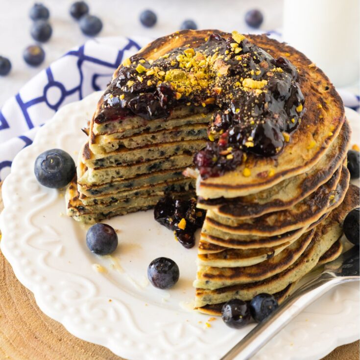 a stack of gluten free blueberry pancakes with homemade blueberry jam on top